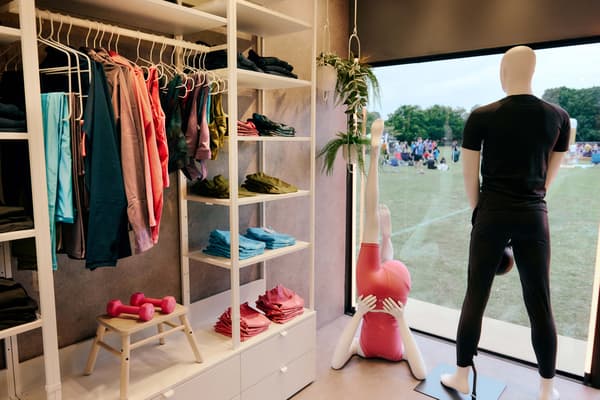 A white open wardrobe in a shop showcasing gym wear, mannequins in front of the window