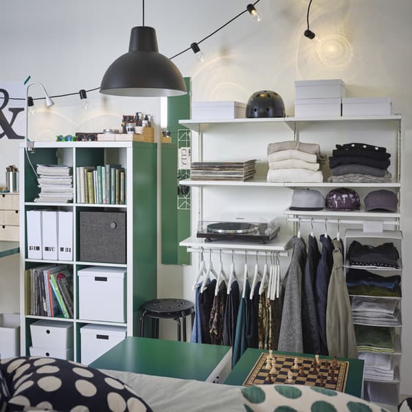 A white open wardrobe with wall-mounted sections with shelves and rails. Both folded and hanging clothes are stored here.