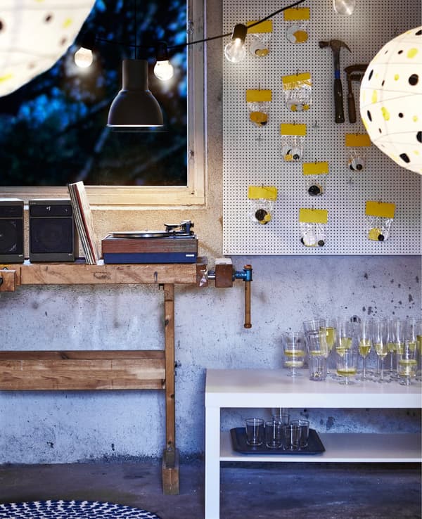 A white pegboard covered with bags of confetti dots beside a work table turned into a DJ area.