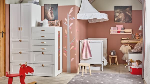 A white/pink traditional children’s room with SMÅSTAD/PLATSA storage, a SUNDVIK cot, and FLISAT children’s stools.