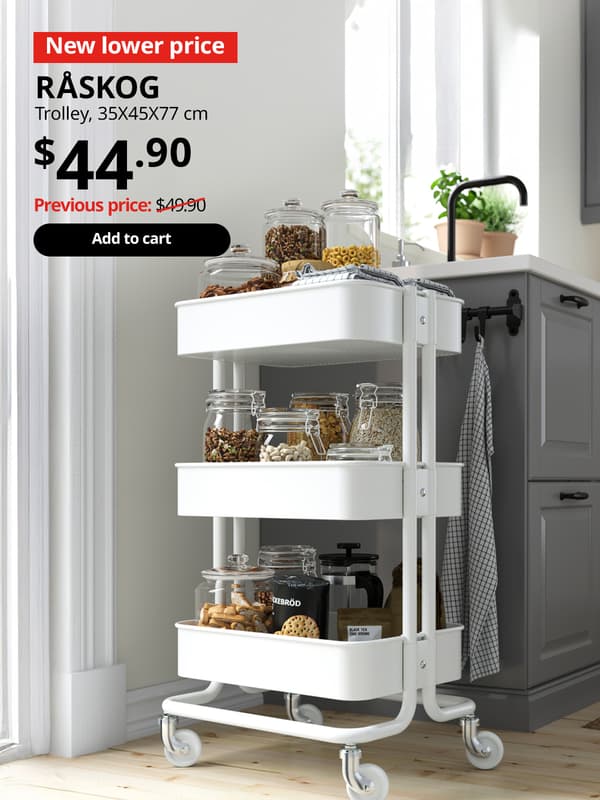 A white RÅSKOG trolley is utilised in the kitchen setting to hold all the dried pantry items. Red tag with white text that reads, "New lower price". Black text overlay image on top-left that reads, "RÅSKOG, Trolley, 35x45x77 cm. $44.90, Previous price: $49.90"