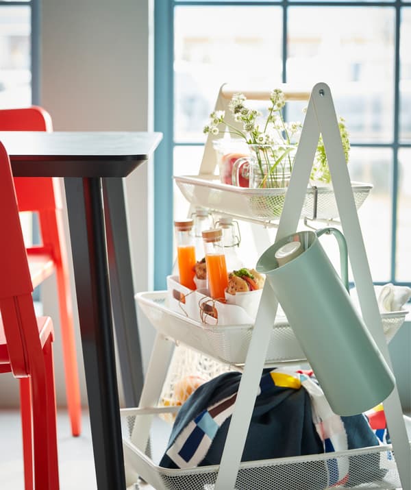 A white RISATORP steel trolley with a wooden handle, filled with a complete breakfast for two.