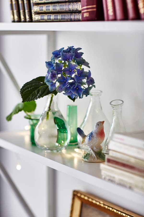 A white shelf is decorated with small glass vases and a bird figurine.