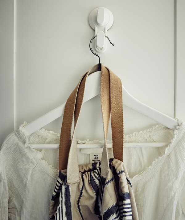 A white shirt and bag on a hanger on a white hook.