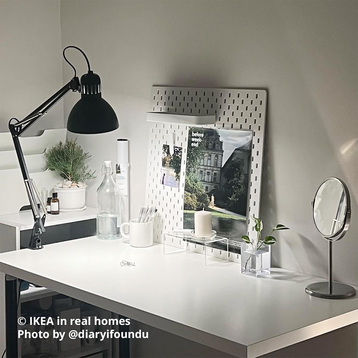 A white SKÅDIS pegboard combination with a dark grey TERTIAL work lamp mounted at the left side of a white LAGKAPTEN desk with black ADILS legs, located at the corner of the bedroom. Photo by instagrammer @diaryifoundu from IKEA in real homes ©
