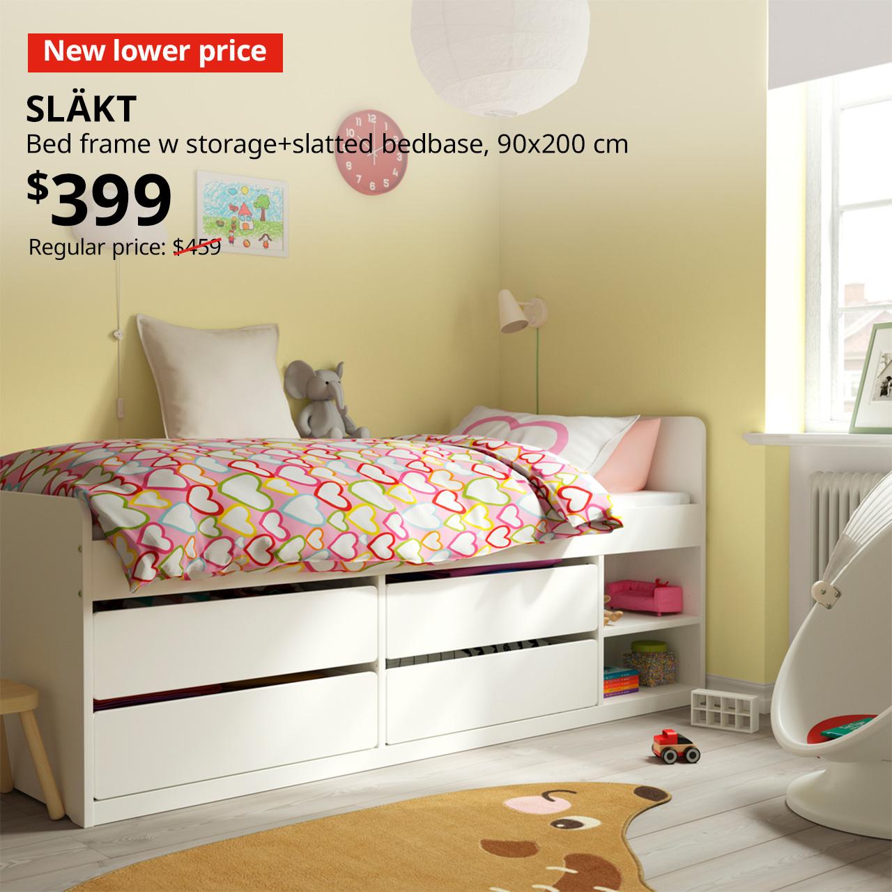 A white SLÄKT bed frame with built-in underbed storage drawers, positioned in the corner of a children’s bedroom, featuring a vibrant yellow wall. A red tag with white text that reads "New lower price", followed by a black text overlay image that reads, "SLÄKT, Bed frame w storage+slatted bedbase, 90x200 cm, $399, Regular Price: $459".