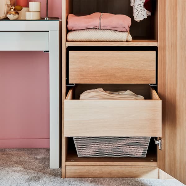 A white stained oak effect wardrobe with drawers, a white dressing table, pink walls and a grey rug.