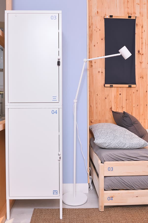 A white storage cabinet with a lock is placed beside a lamp.