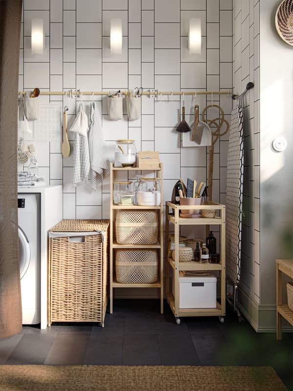 A white-tiled corner has a white washing machine, a RÅGRUND cart, a rail on the wall and a storage shelf made of bamboo.