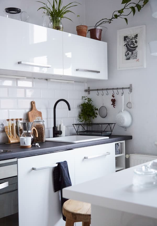 A white tiled kitchen with kitchen island and high-gloss white cabinets.