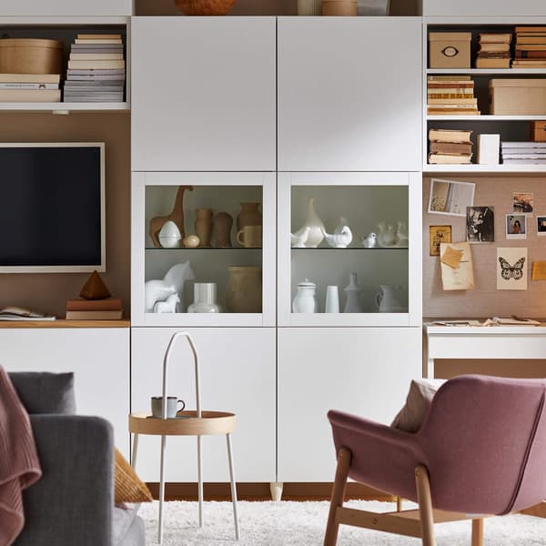 A white TV storage unit with clear doors and decor inside.