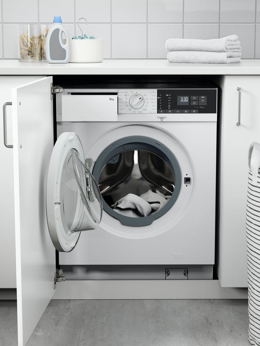 A white TVÄTTAD integrated washing machine in a white kitchen.