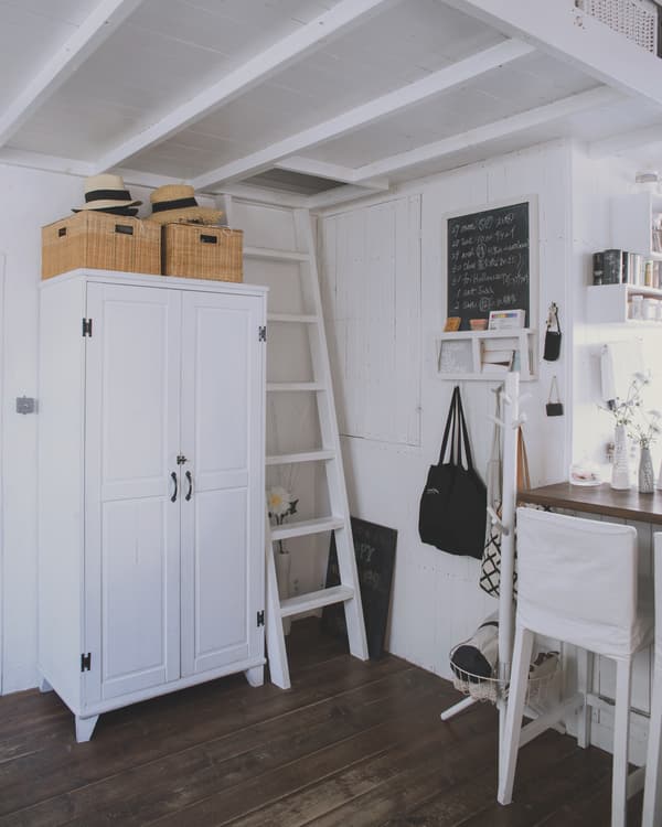 A white wardrobe in a white home with dark wood floors.