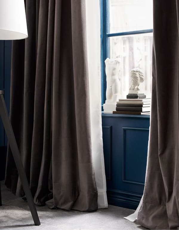 A window with two layers of curtains, one heavy brown, one light white.