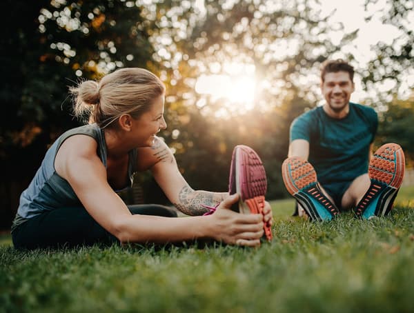 A woman and a man stretching after exercising.