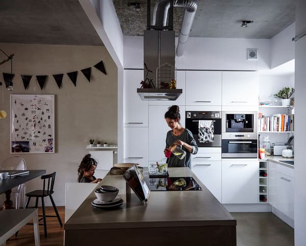 A woman and child in an integrated kitchen and living area.
