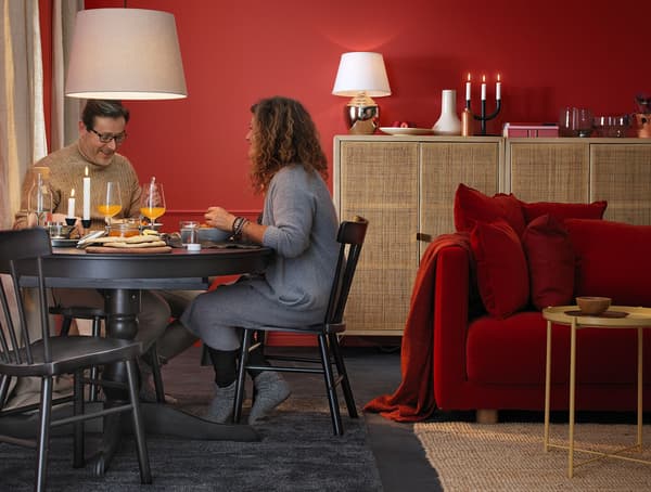 A woman and man sitting at a black dining table eating a meal.
