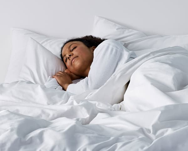 A woman asleep under a duvet.