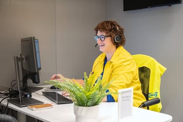 A woman at customer service smiling and talking on the phone.