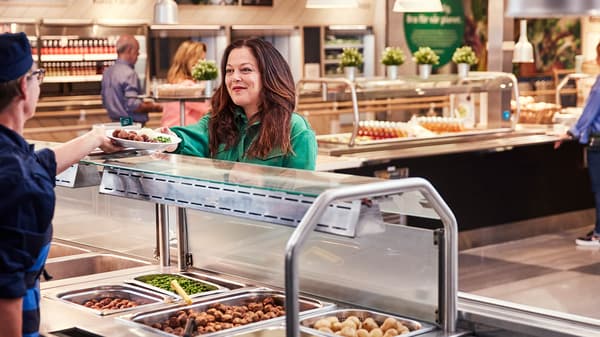 A woman being served a warm plate of lunch at the IKEA Swedish restaurant.