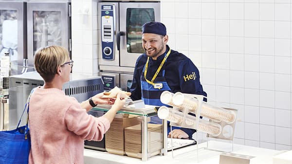 A woman buying an IKEA hot dog from the IKEA bistro