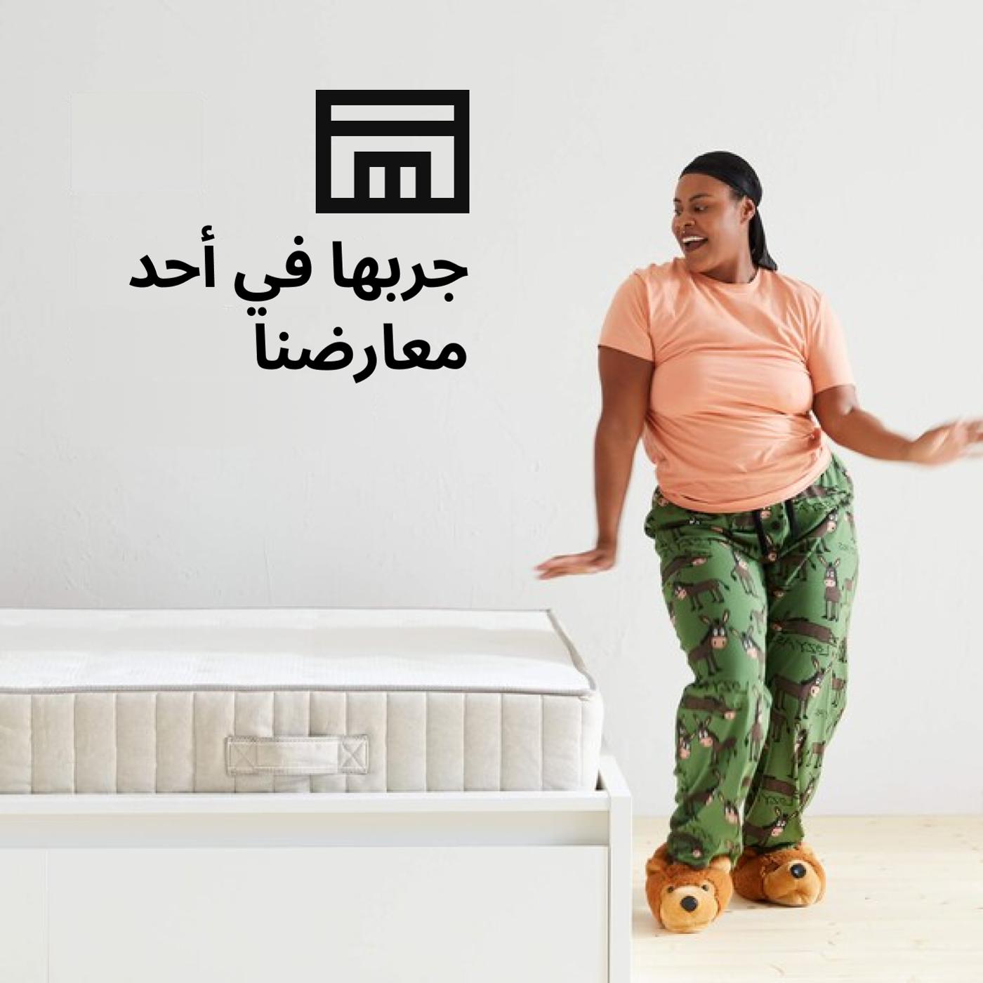 A woman dancing in her pajamas next to a bed and a store box symbol and the text 'Ready to test drive a mattress?' on the image.