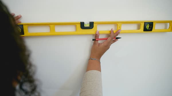 A woman holding a level against a wall.