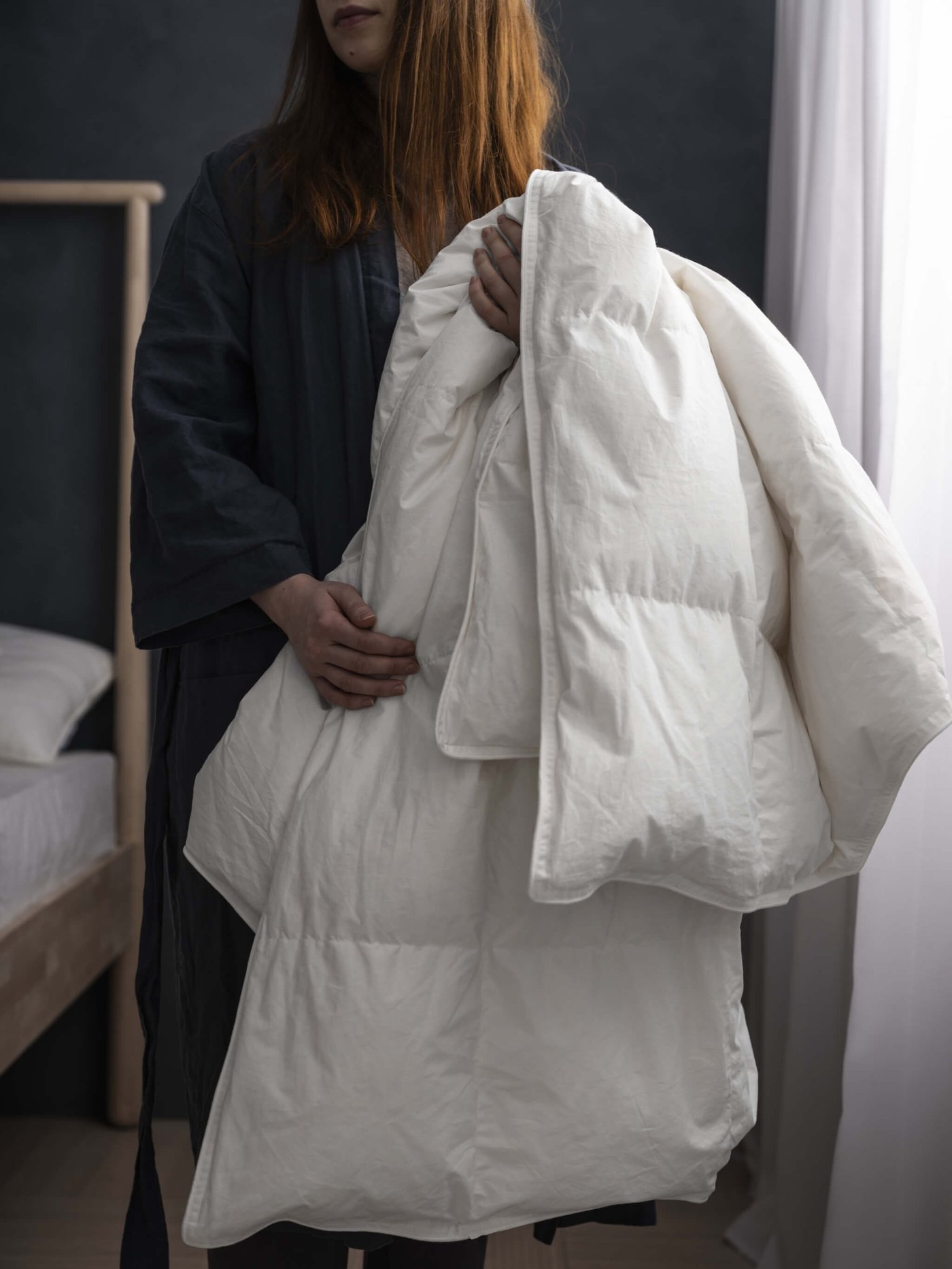 A woman holding a white duvet insert.