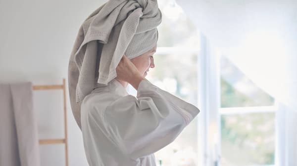 A woman in a gray robe with her hair wrapped in a gray towel.