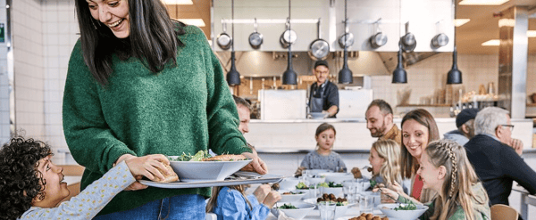 A woman in a green sweater holding a tray of food with people