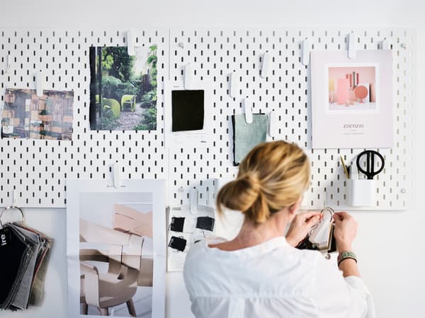 A woman in a white shirt arranging pictures on the board.