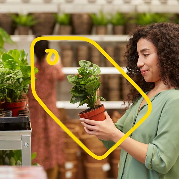 A woman in an IKEA store in the plant department above an IKEA image of a price tag