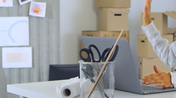 A woman in blue-and-yellow IKEA co-worker clothes holds up colour samples while looking across the desk she’s sitting at.