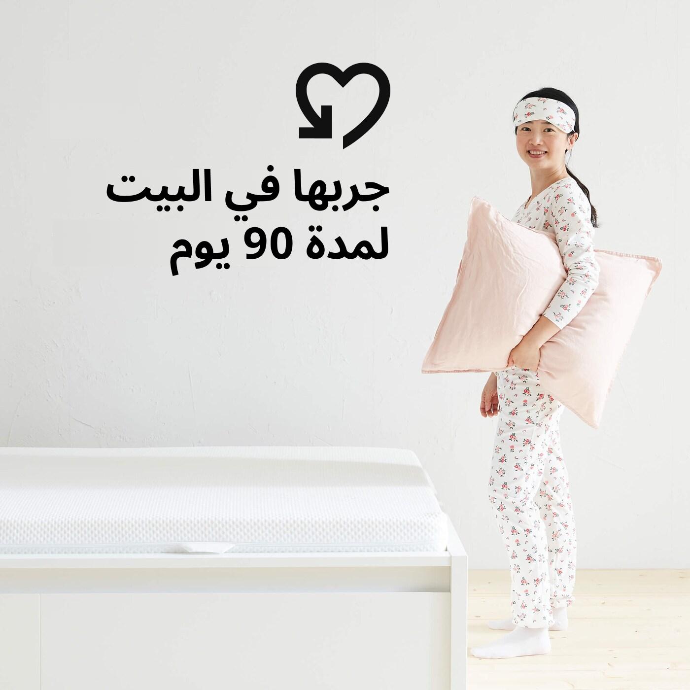 A woman in her pajamas holding a pillow next to a bed and a heart graphic and the text 'Try it at home for 90 days' on the image.