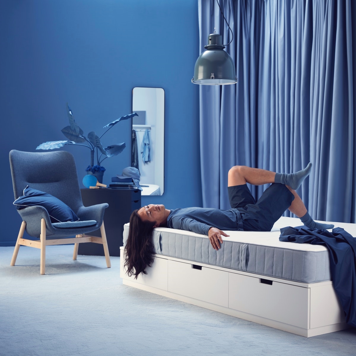 a woman is lying on a mattress with her legs crossed and smiling.