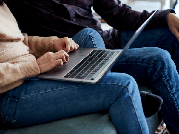 A woman is sat typing on a laptop held on her lap