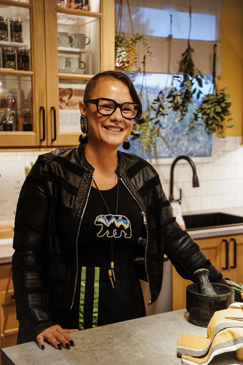 A woman is smiling while standing at a kitchen island.