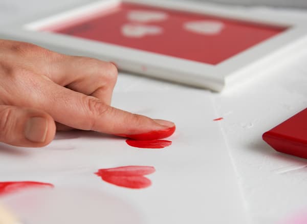A woman makes her own art as a gift by making hearts with her fingertips.