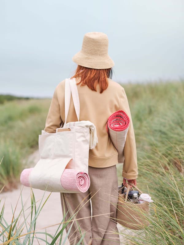 A woman outside facing away from the camera with a bag around her shoulder.
