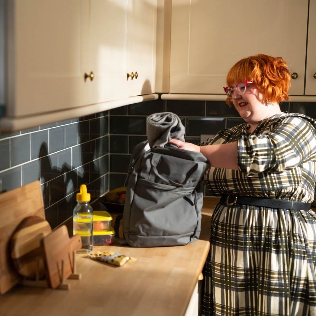 A woman packing her backpack for an outdoor trip