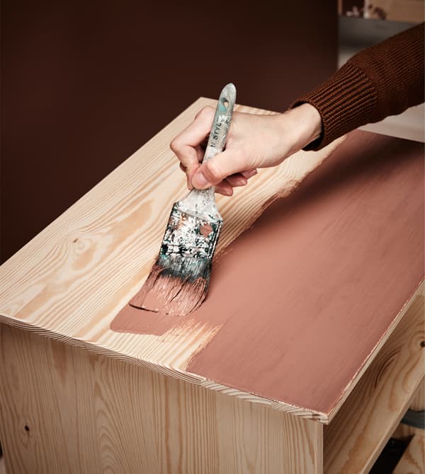 A woman paints a bedside table