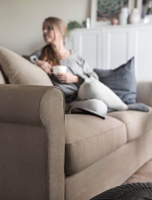 A woman relaxing on a sofa with a cup in hand.