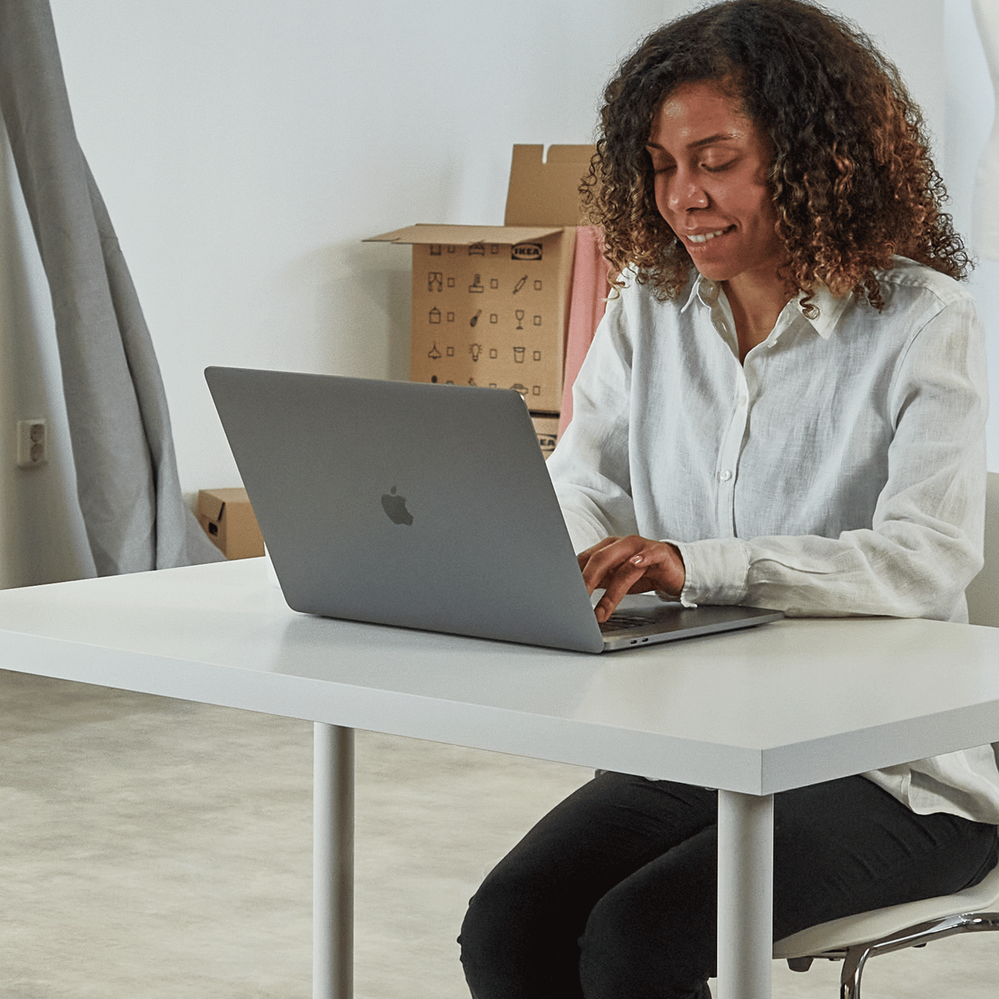 A woman sits behind her laptop and plans her ideal wardrobe with our PAX planner.