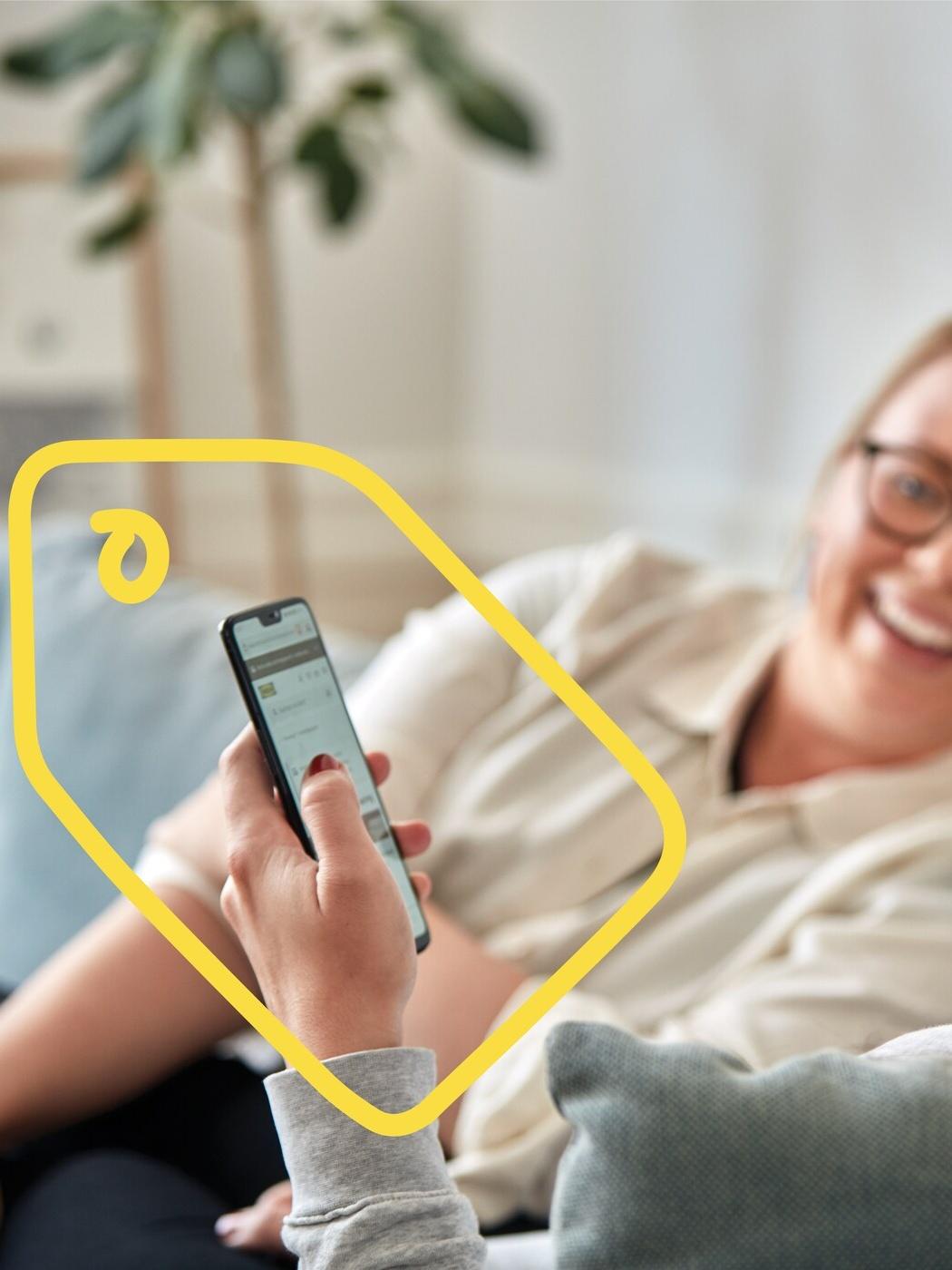 A woman sits on her phone shopping at IKEA with a friend