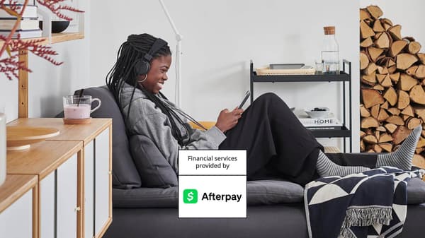 A woman sitting on a chaise smiling at her phone.