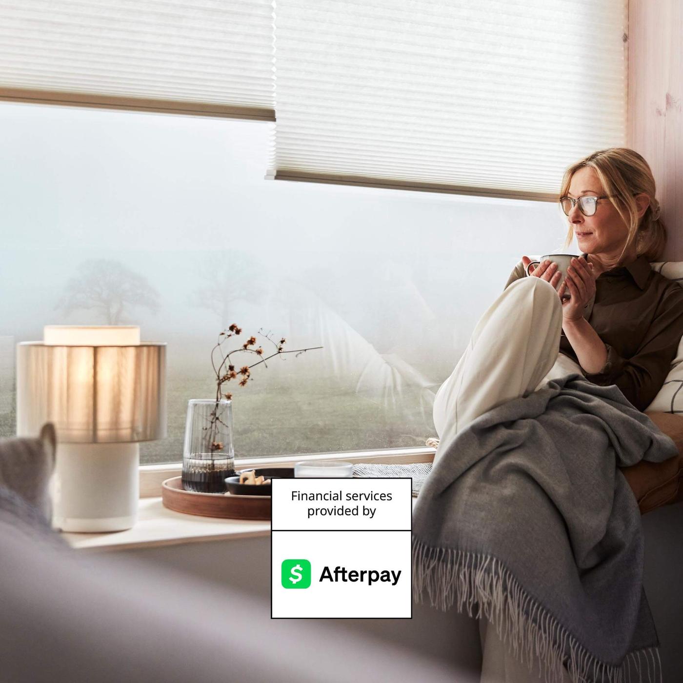 A woman sitting on a ledge holding a cup with the Afterpay logo graphic on the image.