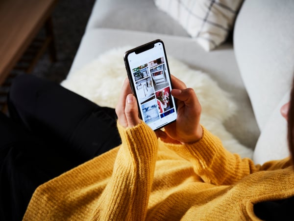 A woman sitting on a sofa looking at the IKEA app