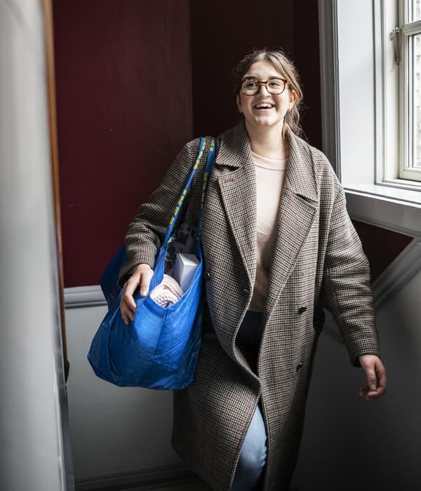 A woman smiling carrying a blue FRAKTA bag.