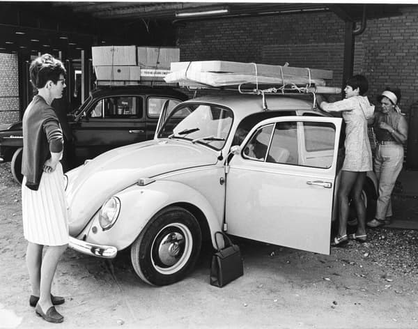 A woman stands in front of the car, watching as IKEA products are loaded for transport

