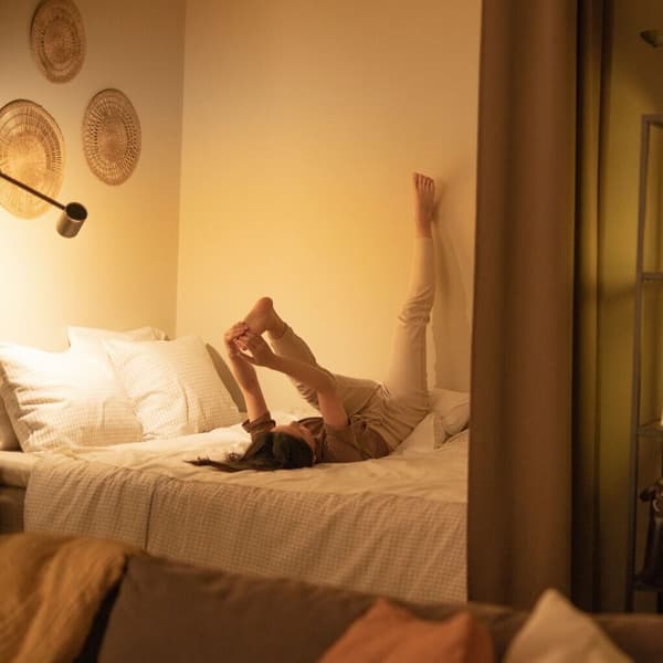 A woman stretching her leg against wall.